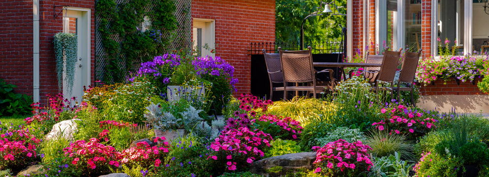 Blossoming flowers in a garden in a residential backyard with patio furniture; Hudson, Quebec, Canada