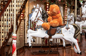 carousel in the form of a horse with a red teddy bear toy in the New Year's city in winter