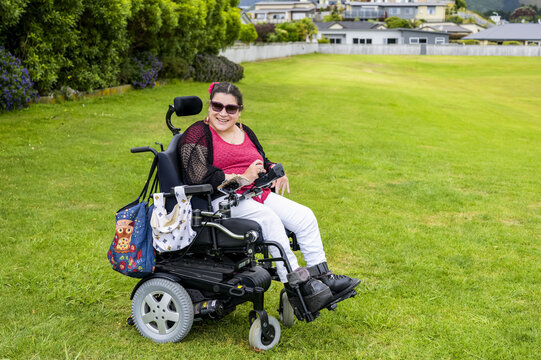 Maori woman with Cerebral Palsy in a wheelchair on a grass field in a park area; Wellington, New Zealand