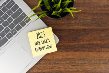 2023 New Year's resolutions text on adhesive notes on top of office desk with laptop