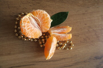 Mandarin slices on a wooden table with golden beads