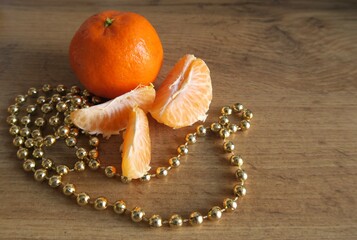 Mandarin slices on a wooden table with golden beads