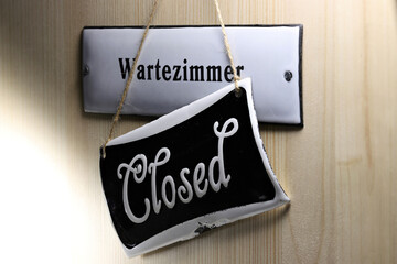 enamel sign on the door to the (closed) waiting room of a German doctor's office
