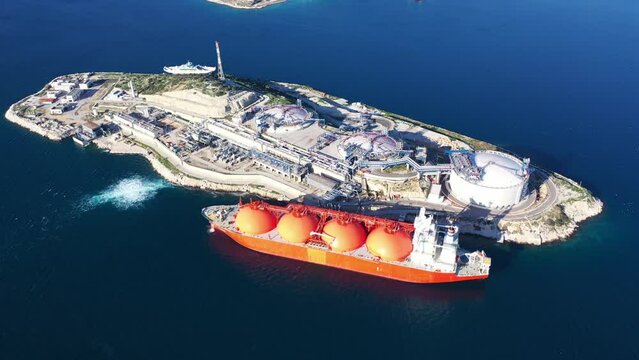 Aerial drone video of LNG (Liquified Natural Gas) tanker anchored in small gas terminal island with tanks for storage