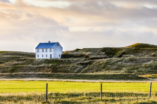White house on grass knoll in Southern Iceland; Myrdalshreppur, Southern Region, Iceland
