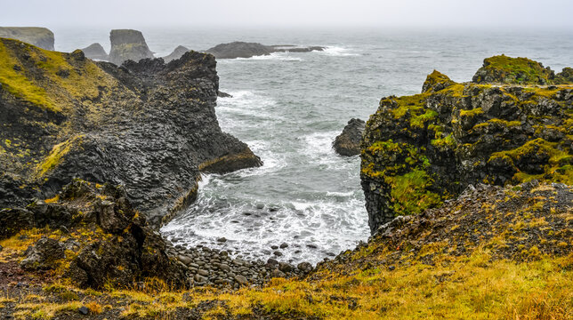 View of the rugged coastline with cliffs and mossy rocks, Arnarstapi; Snaefellsbaer, Western Region, Iceland
