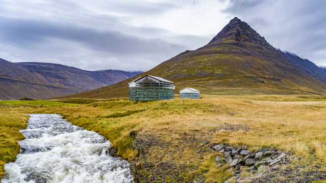 Weathered structures on a remote landscape beside a rushing river; Isafjardarbaer, Westfjords, Iceland