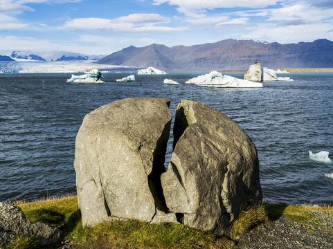 The glacial lake, Jokulsarlon, flows through a short waterway into the Atlantic Ocean, leaving chunks of ice on a black sand beach, Vatnajokull National Park; Hornafjordur, Eastern Region, Iceland