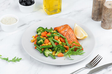 Baked salmon with vegetables on a gray background