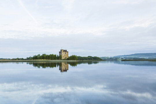 Symmetrical reflections of Castlebawn tower house on Lough Derg on a summer day; Scariff, County Clare, Ireland
