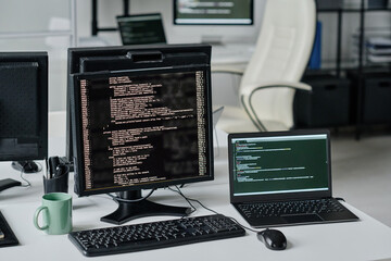 Horizontal image of computer monitors with program codes on screens in modern office