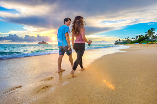 A couple walks on Lanakai beach on the Hawaiian island of Oahu at sunset; Lanakai, Oahu, Hawaii, United States of America