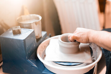 Man potter working on potters wheel making ceramic pot from clay in pottery workshop. art concept