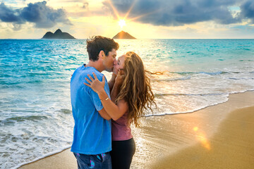A couple stands kissing on Lanakai beach on the Hawaiian island of Oahu at sunset; Lanakai, Oahu, Hawaii, United States of America