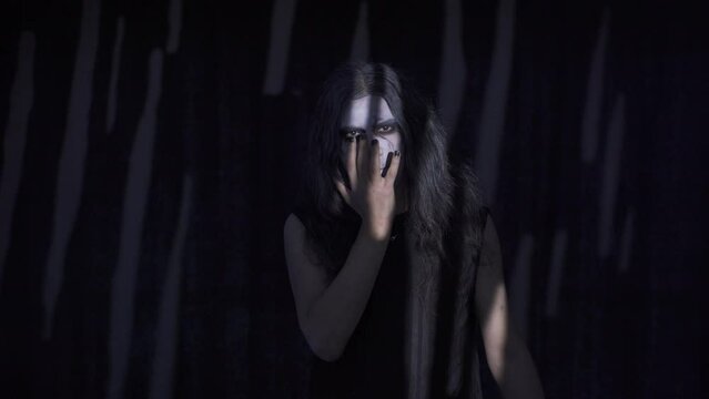 Goth man, lifestyle.
Gothic man running his fingers over his face. Black background.
