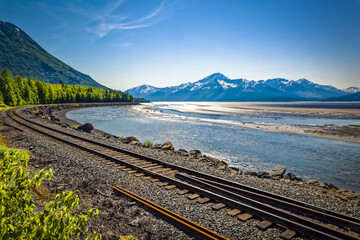 Alaska Railroad track along with Turnagain Arm of Cook Inlet, Chugach Mountains in the background, South-central Alaska in summertime; Portage, Alaska, United States of America