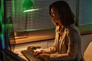 Young woman concentrating on her online work on computer, she typing codes on keyboard working in...