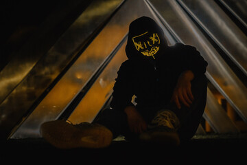 Mann in einem Hoodie mit einer gelben LED Maske vor einem geometrischen Kunstwerk.