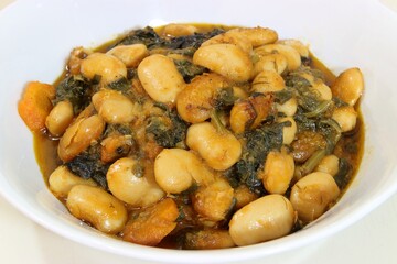 Butter beans, spinach, carrot and tomato sauce dish. Closeup, selective focus