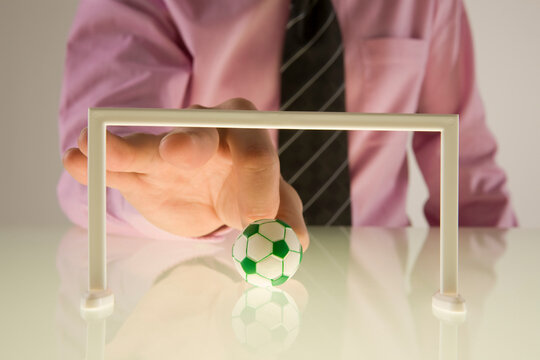Businessman Playing With Miniature Football