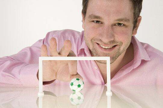 Businessman Playing With Miniature Football