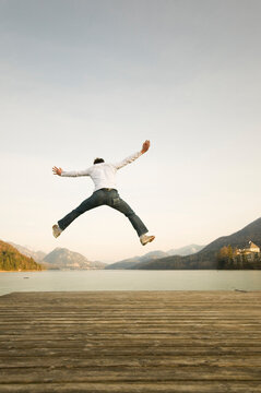 Man on Dock Jumping High in the Air, Fuschlsee, Salzburger Land, Austria
