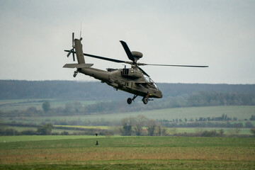 Fototapeta na wymiar close-up three quarter view of British army Boeing Apache Attack helicopter (AH-64E ZM722 ArmyAir606) transition from hover to flight, Wiltshire UK