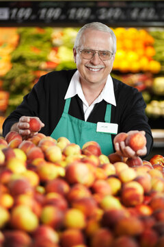 Grocery Clerk Arranging Peaches in Produce Aisle