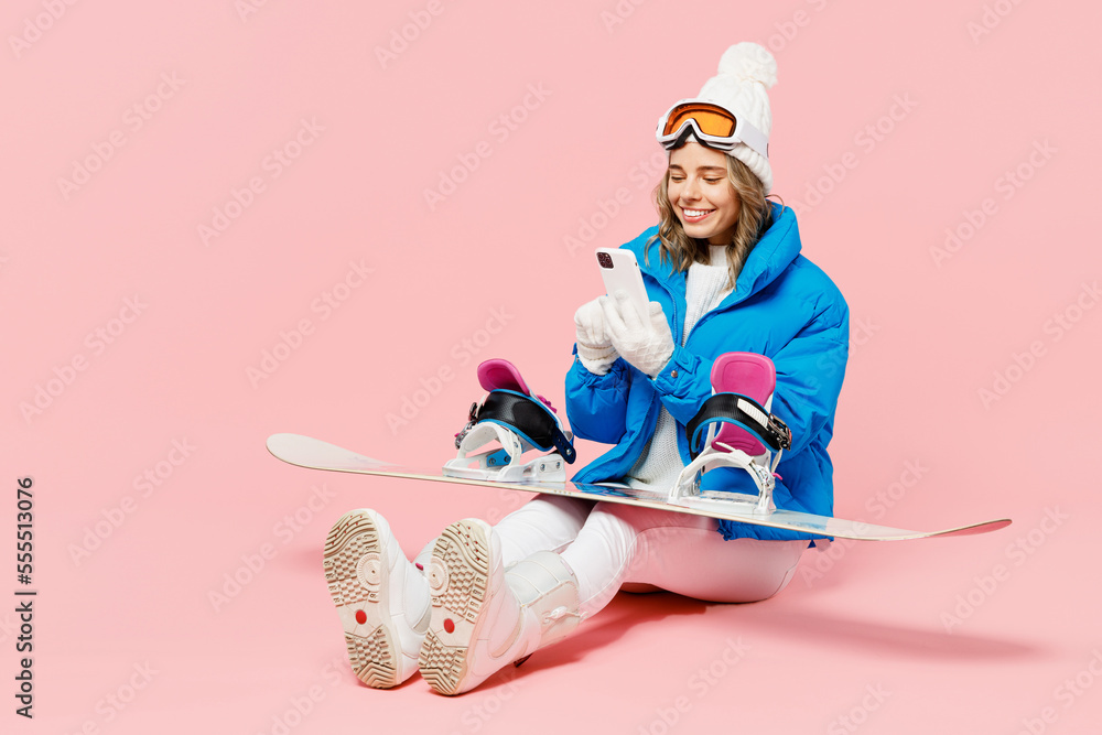 Wall mural snowboarder woman wear blue suit goggles mask hat ski padded jacket sitting hold use mobile cell pho