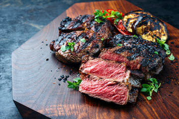 Barbecue dry aged angus rib-eye beef steak with grilled vegetable and spice served as close-up on a...