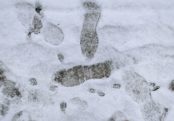 Footprints on the white snow lying on the road in winter. Photography, texture.