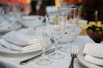 table setting for a festive dinner. empty wine glasses, tableware and snacks.