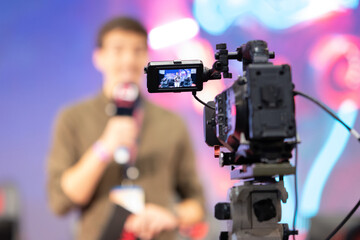 A movie camera shoots a man on stage at the game expo