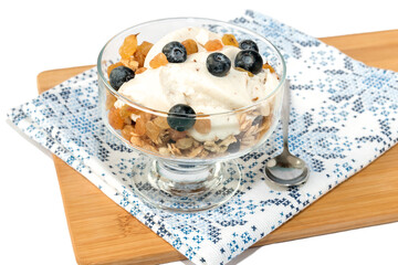 In a glass vase, a healthy morning breakfast with muesli, yogurt, raisins, blueberries.
