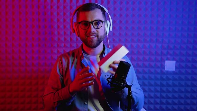 Excited overjoyed young male blogger unpacking boxe with new smartphone and doing live streaming. Attractive man using smart phone camera for creating content