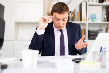 Puzzled businessman looking at papers during work in office