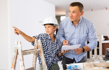 Father with little son talking about repair work in the apartment