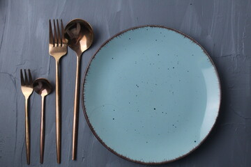 set table. Spoon fork and plate stands on a gray background with a place for food and text copyspace