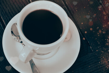 Cup of filter coffee or espresso on a wooden table with heart pattern and bokeh light for Valentine's Day