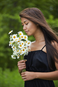Woman Smelling a Bouquet of Daisies