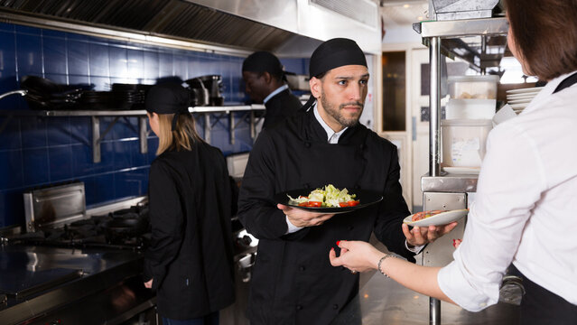 Staff Of Restaurant With Head Chef Working Together In Kitchen.