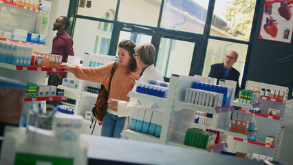 Obraz premium Young customer fainting in pharmacy and losing balance, feeling off and unconscious. Pharmacist and clients helping woman with dizziness sensation, falling down in drugstore shop. Dutch angle.