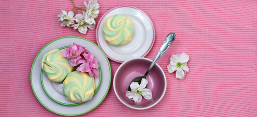 Banner with Colorful fluffy striped marshmallows on saucers on a pink knitted background