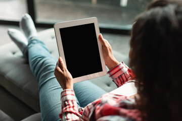 New app for chat. Millennial black female using tablet with blank screen, ordering goods remotely