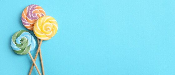 Delicious lollipops on light blue background with space for text