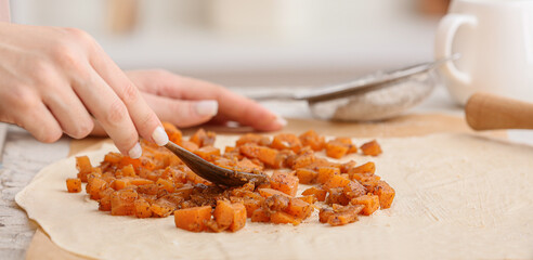 Woman cooking tasty pumpkin pie on table, closeup