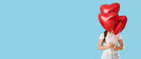 Woman holding heart-shaped balloons on light blue background with space for text. Valentine's Day celebration