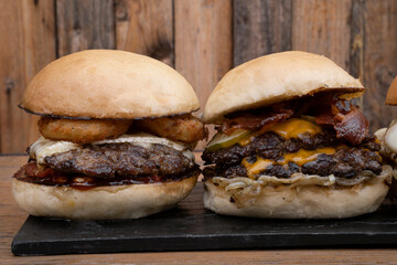 Big tasty burgers. Closeup view of two multilayer burgers in a black dish with a wooden background. 