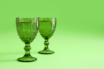 Glasses of cocktail on green background