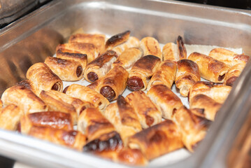 Buffet table with a chaffing dish full of wrapped pigs in a blanket for the party guests to eat